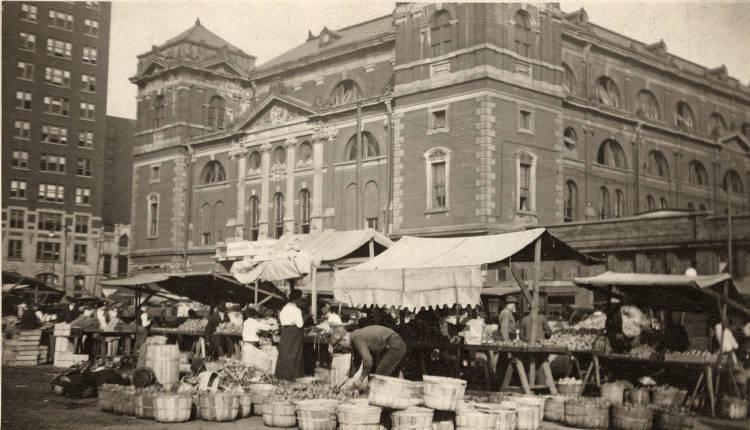The street in front of Tomlinson Hall is full of market stalls. People are shopping.