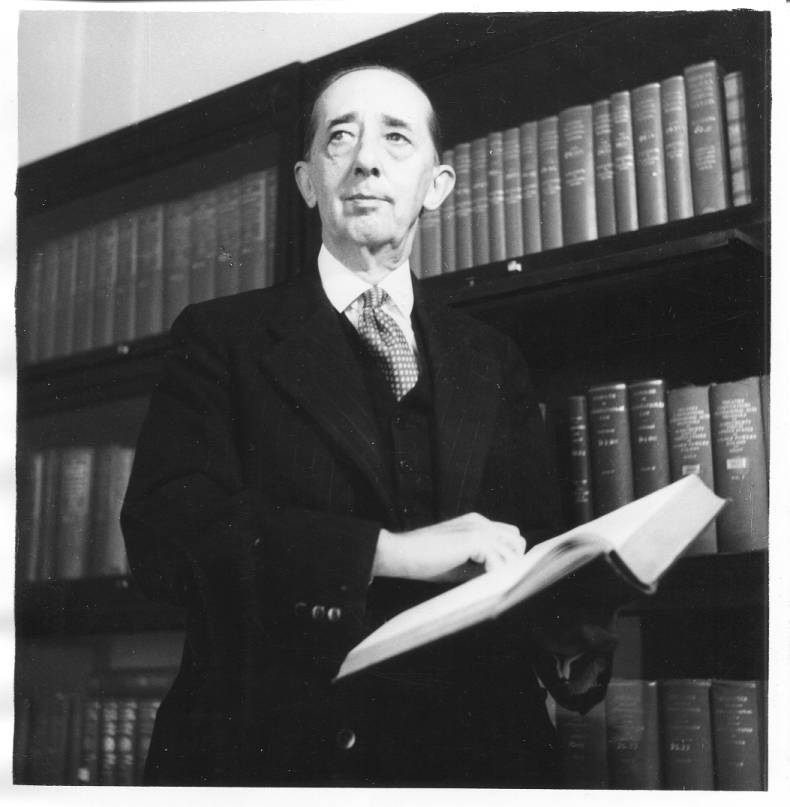 Portrait of Bowers standing in front of a bookshelf.