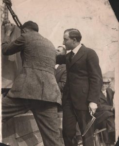 Henry Eitel, the nephew of James Whitcomb Riley, holding trowel, assists another man in laying Central Library cornerstone, 1916