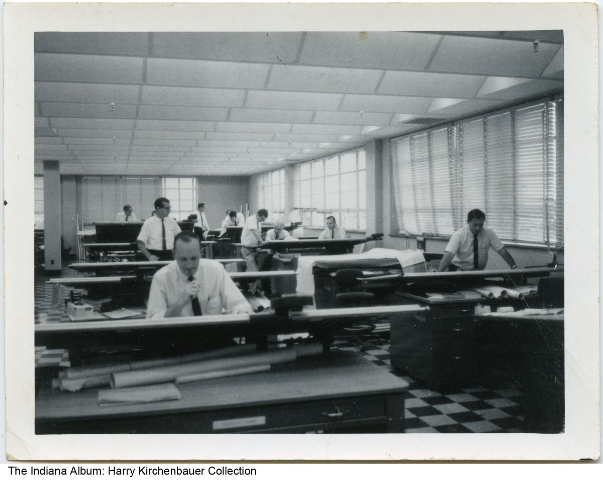 Several men work at drafting tables in an office.