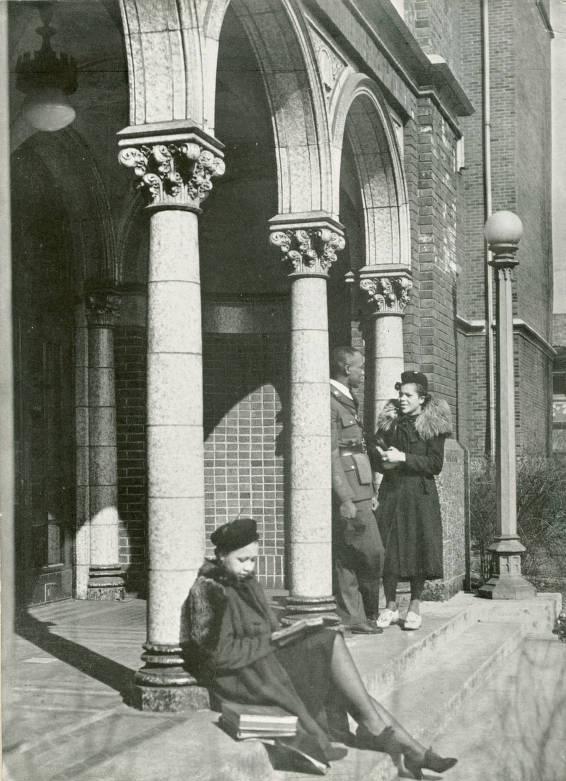 A student reads outside the front entrance of Crispus Attucks High School while two others converse nearby.