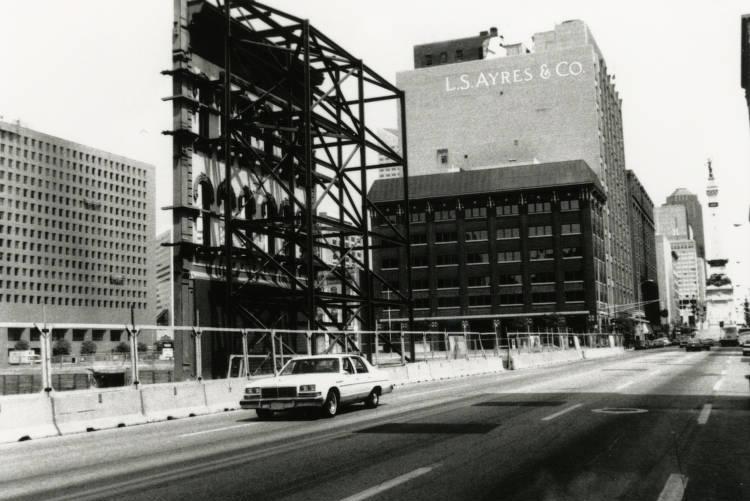 Scaffolding lines the front of a building. The sidewalk is fenced off.
