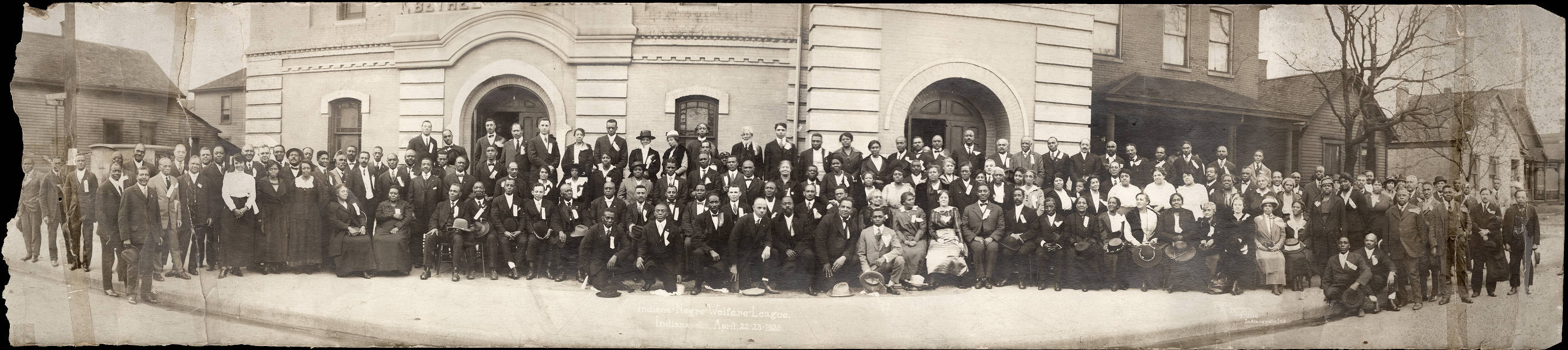 A large group of African American people stand together outside of a building. 