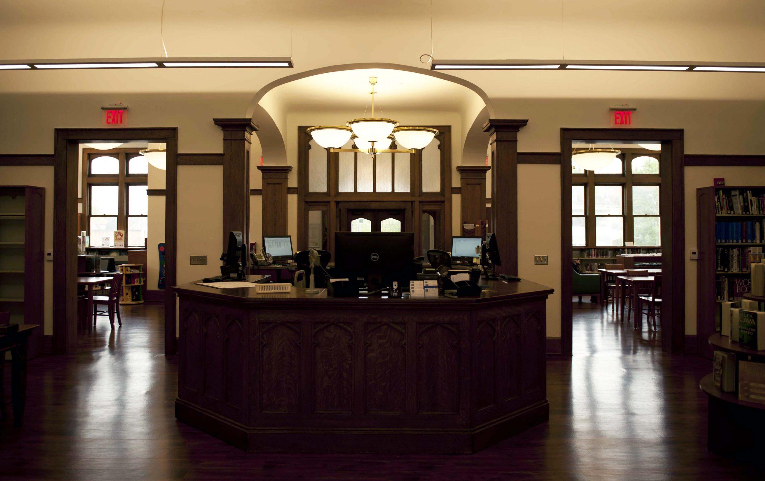 A large wooden desk sits in the middle of an entryway. Two entrances behind it lead to other rooms.