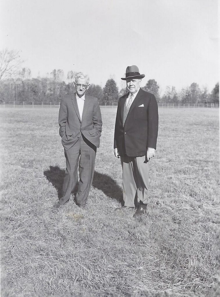 Two men stand in a field.