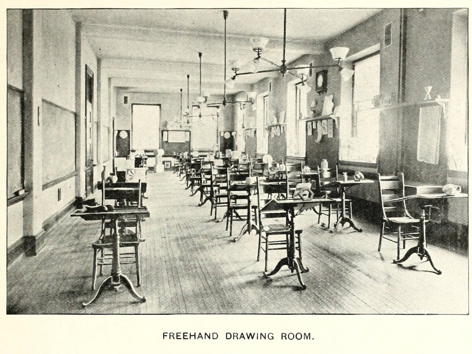 A large classroom filled with individual drawing desks in three rows. 