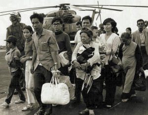 South Vietnamese refugees walk across a U.S. Navy vessel, 1975