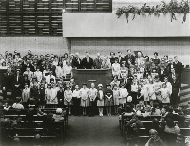A large group of people stand together in a church. 