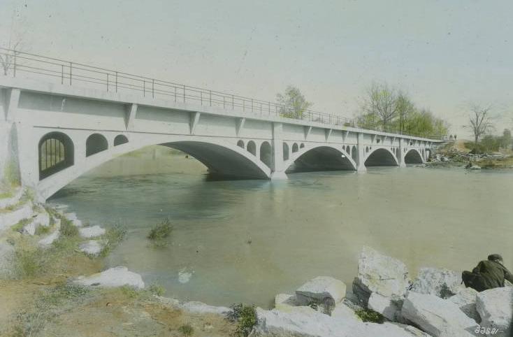 A four-arch concrete bridge spans a river.