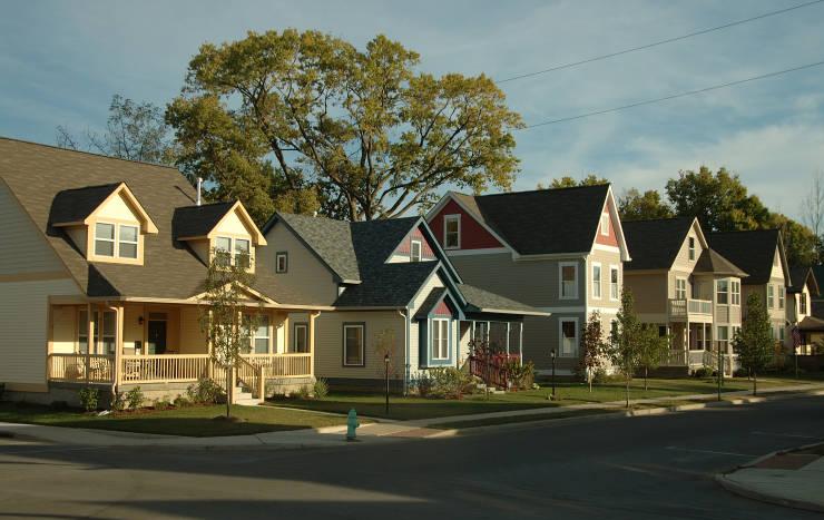 A row of attractive houses with well-tended yards lines a street.