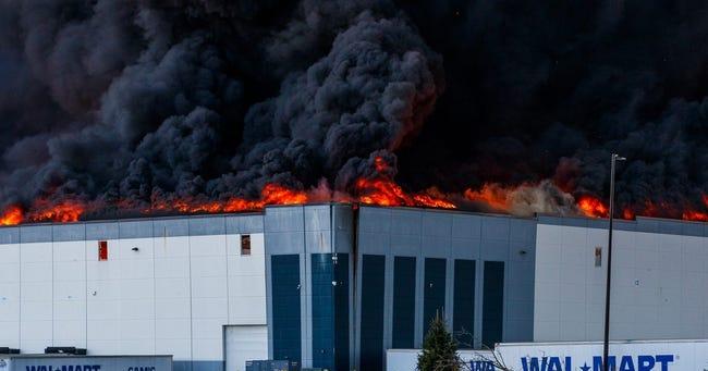 A large cloud of black smoke and flames blots out the night sky above a Wal Mart warehouse.