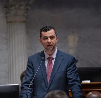 A man stands talking into a microphone.