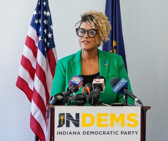 Myla Eldridge stands behind a podium with the American flag and the Indiana State flag behind her.