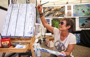 Artist working on a painting in front of her booth at OneAmerica Broad Ripple Art Fair, May 20, 2018