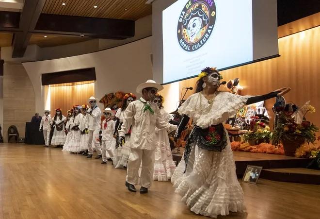 A group of dancers dressed in white perform on a stage.