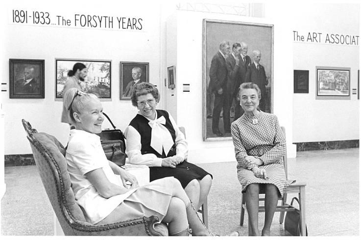 Three women sit together. Art is on the walls in the background.