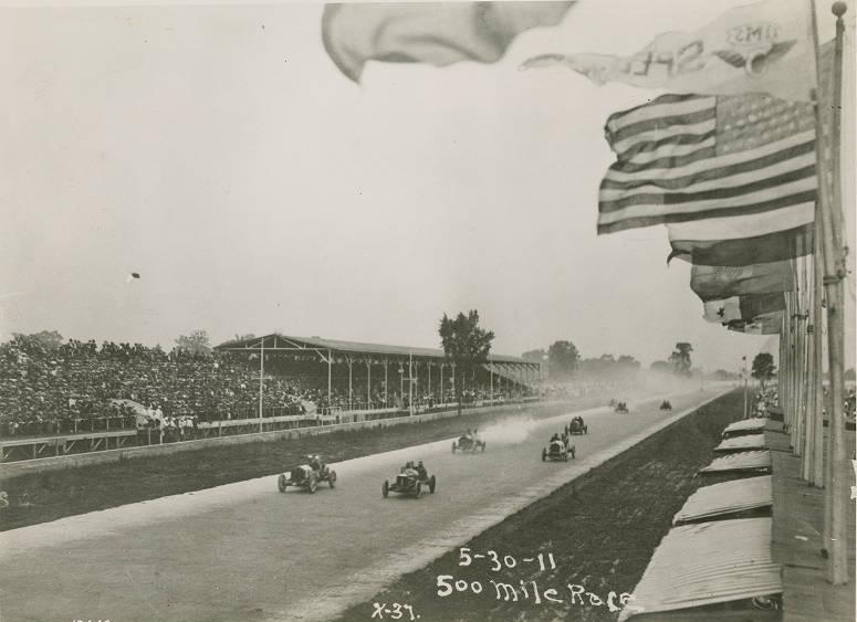 Race cars drive down the main stretch of a track.