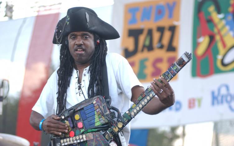 A man in a pirate hat plays a homemade looking instrument.