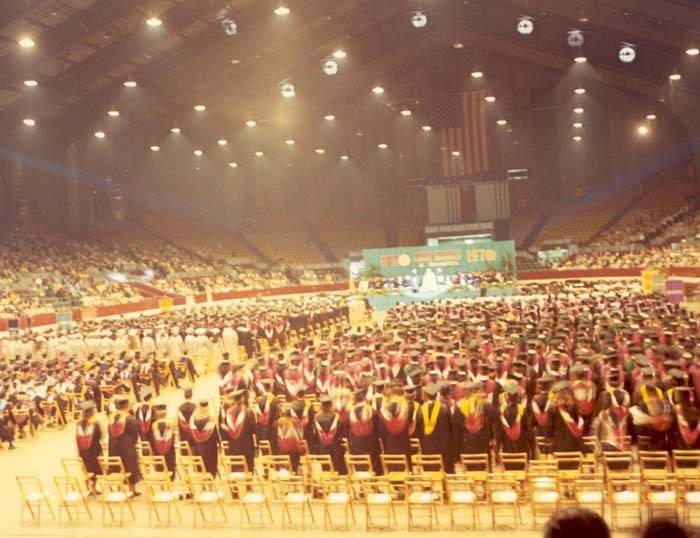 View of the interior of a stadium filled with students wearing academic regalia.