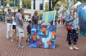 Visitors look over work by artist Charles McNally during the 2018 Monument Circle Art Fair.
