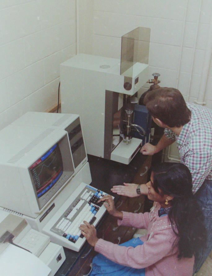 Two people sit at a desk and work on a computer.