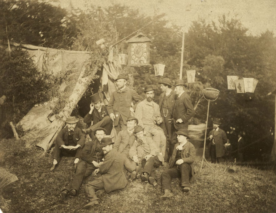 A group of young men pose together outside of a tent.