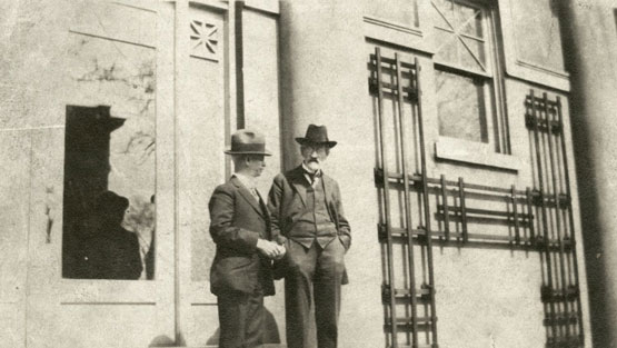 Two men stand in front of a building.