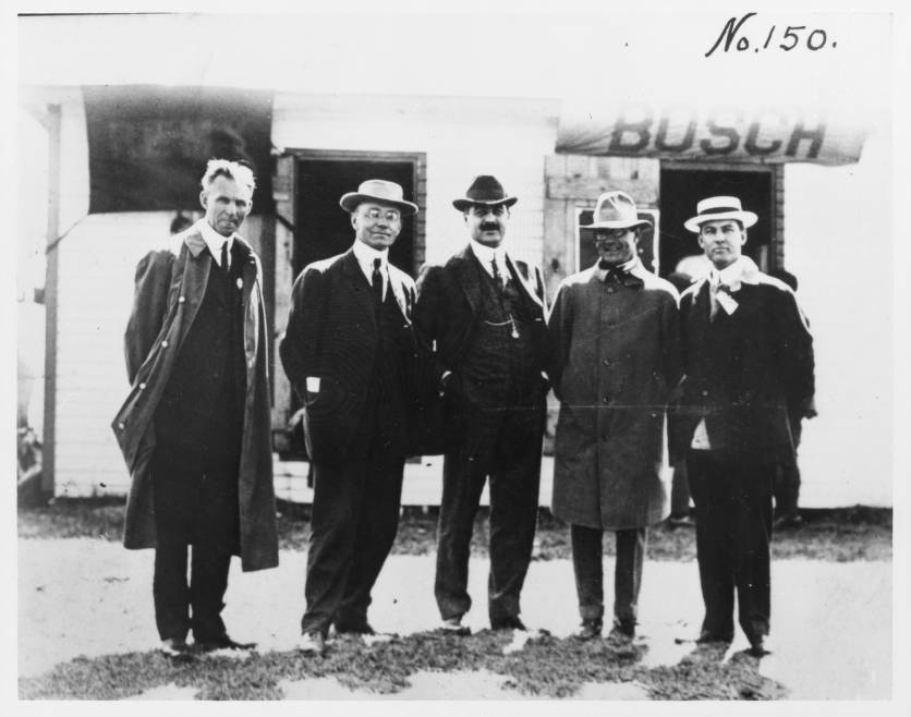 Five men in suits stand together for a photograph. 