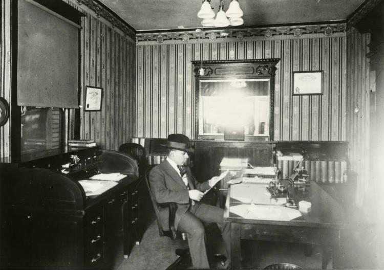 Ransom sits in a chair at a desk. 