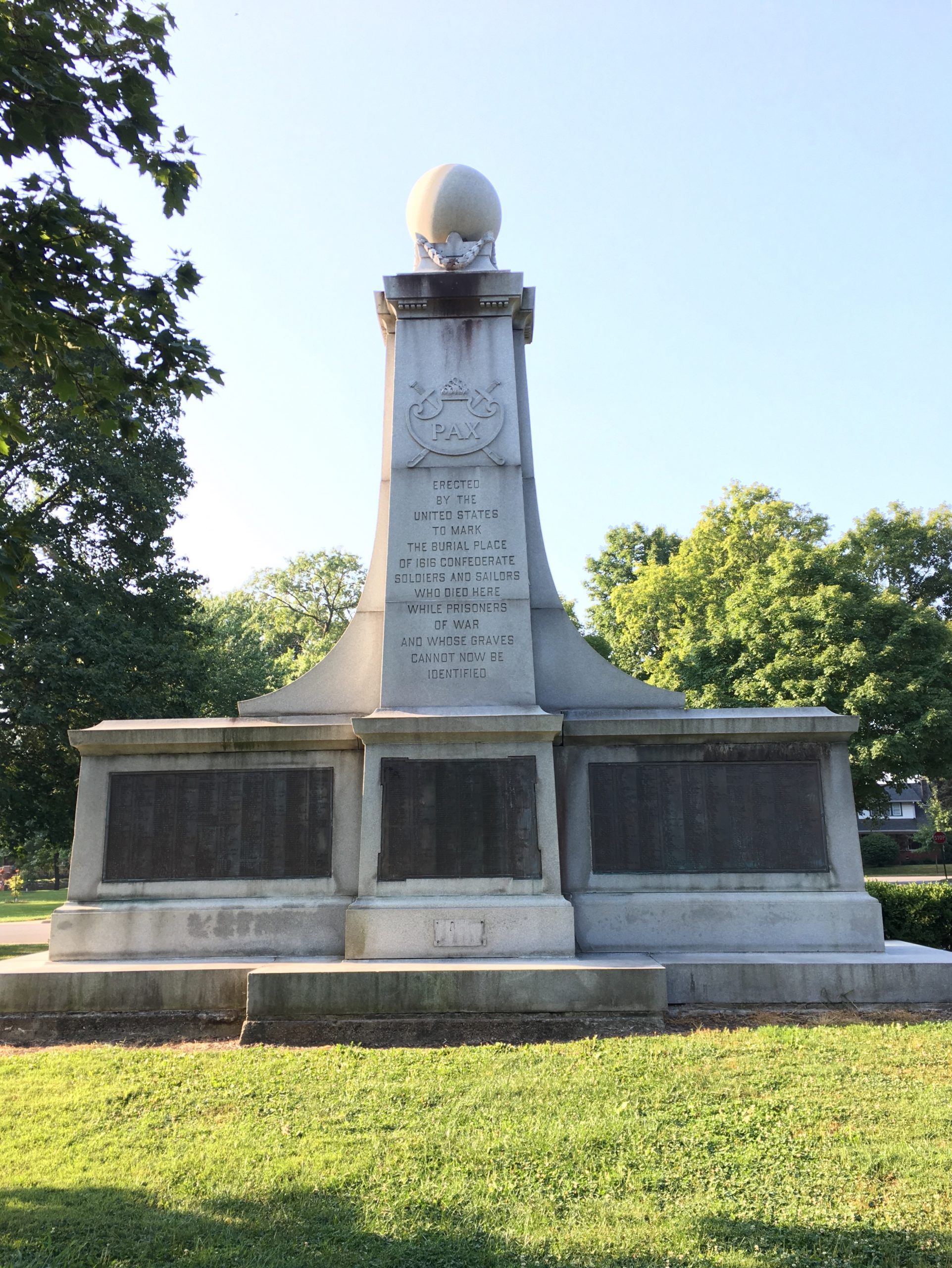 The white stone monument topped by a sphere has three large plaques on the base and the word "PAX" followed by the words "Erected by the United States to mark the burial place of 1616 confederate soldiers and sailors who died here while prisoners of war and whose graves cannot now be identified."