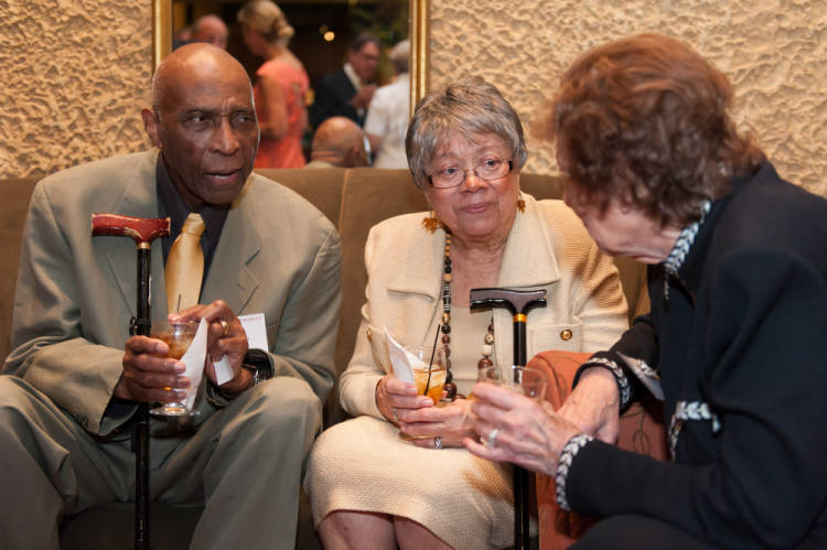 An elderly George Rawls and Lula Rawls sit together on a sofa and talk to another woman.