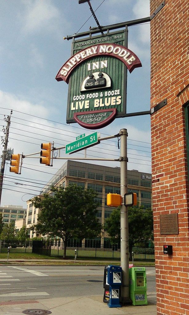 A sign attached to a brick building. The sign says Slippery Noodle Inn, Good Food and Booze. Live Blues. 