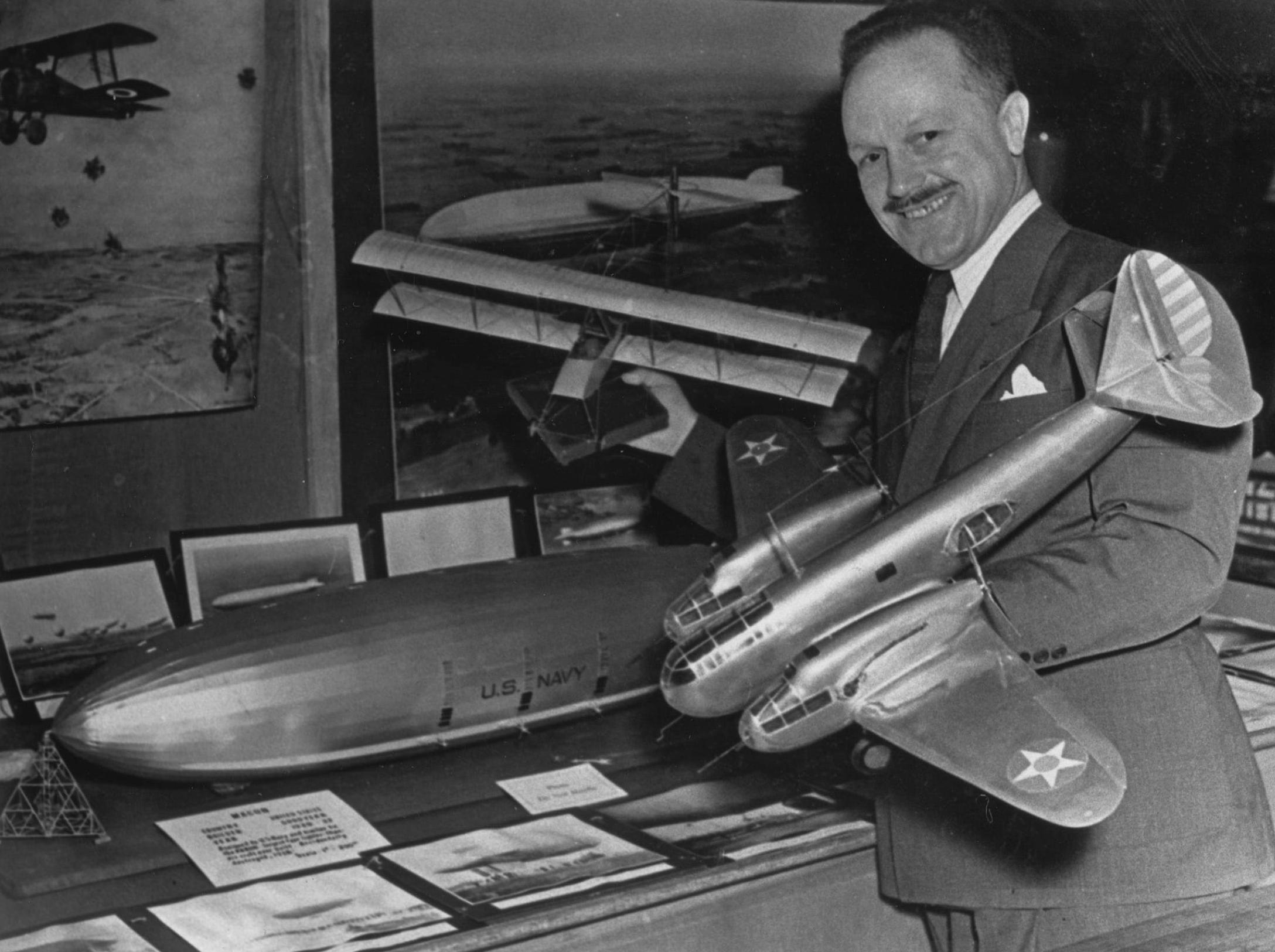 Cook holds a model plane in each hand. 