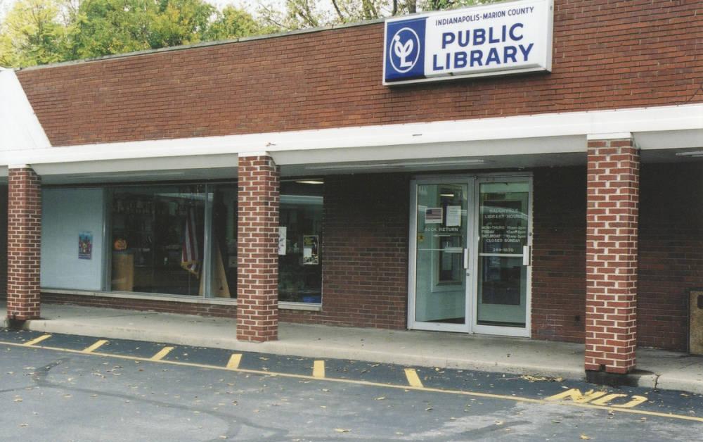 Exterior entrance to a library in a brick shopping center.