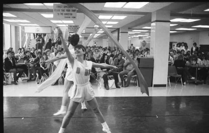 Two people dance with ribbons while a crowd watches.