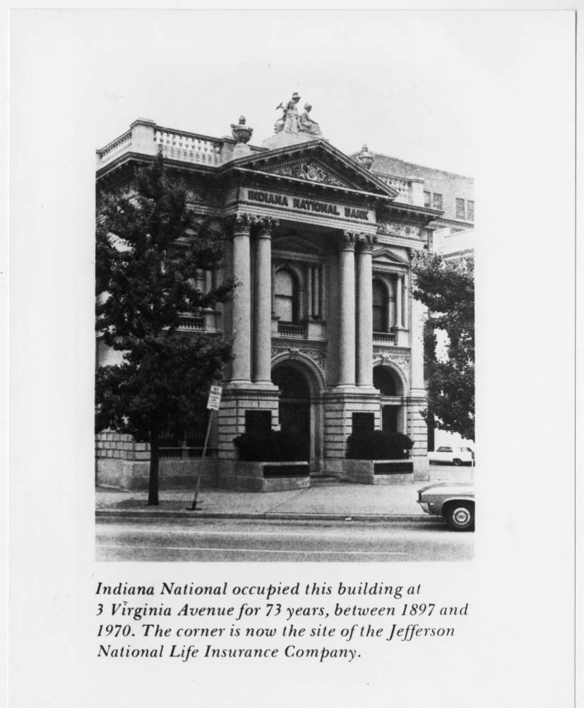 The two-story, Neoclassical building is made of stone and has a balustrade, pediments with friezes inset and columns at the entrance.