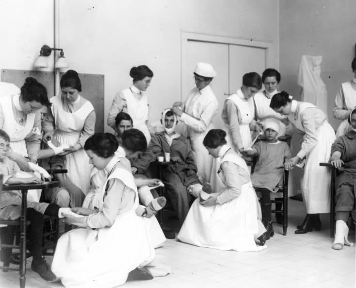 Nursing students in uniform practice nursing techniques with children.