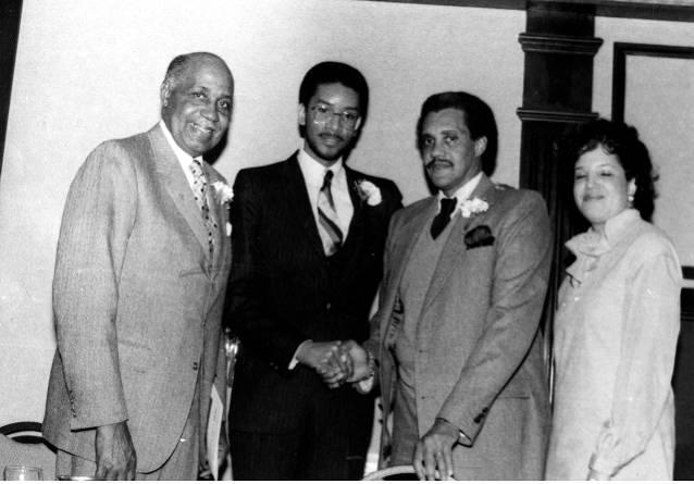 Four people stand together.