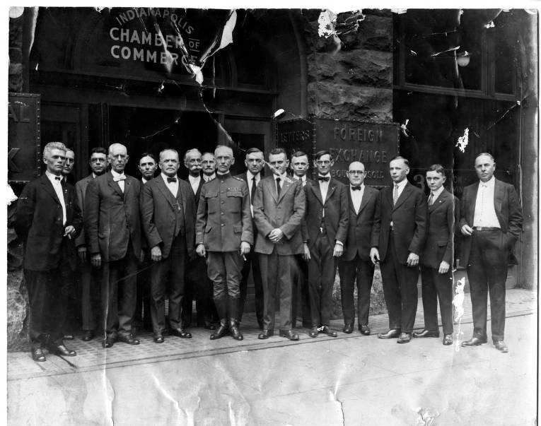 A group of men in suits stand in front of a building.