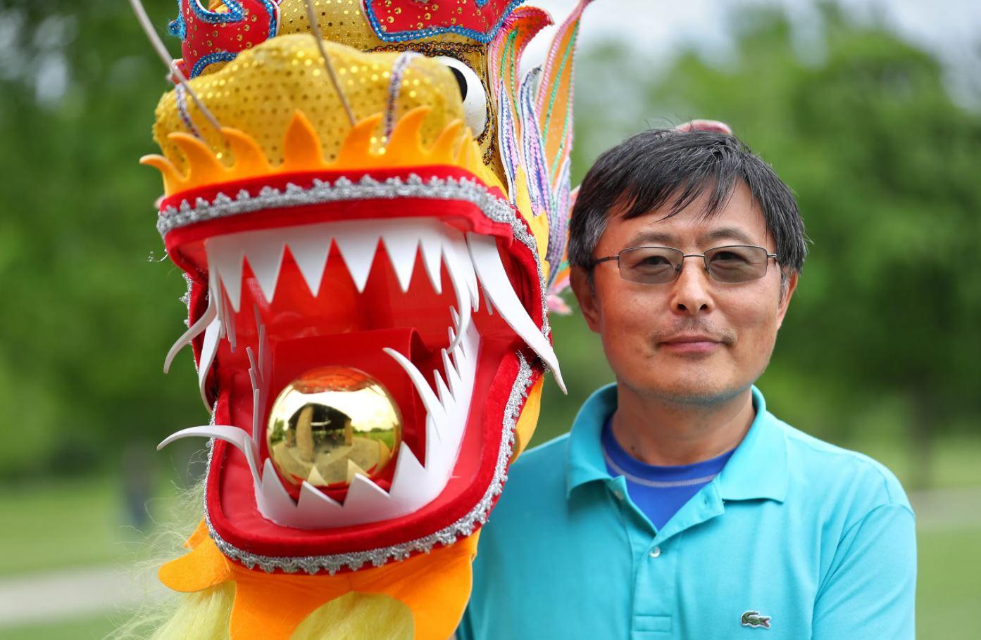 A man stands next to a large dragon puppet.