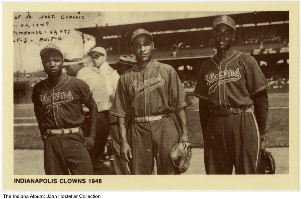 Three men in baseball uniforms stand in a baseball field.