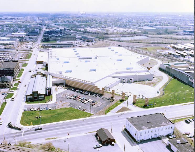Aerial view of a sprawling, low, almost hexagonal building. The warehouse-looking building has a flat white roof.