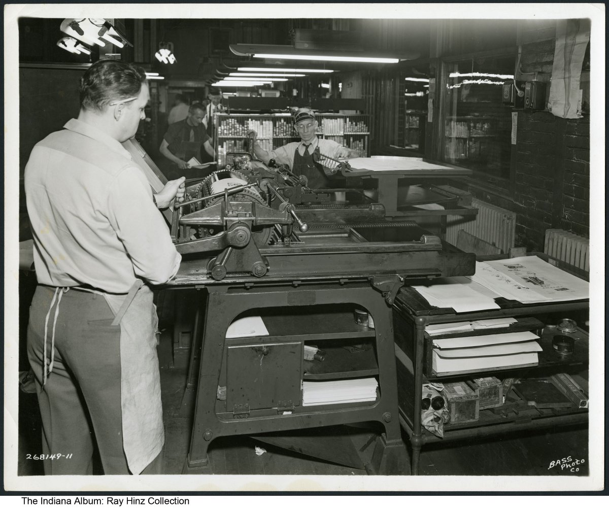 Three men working at a printing press in a large room. 