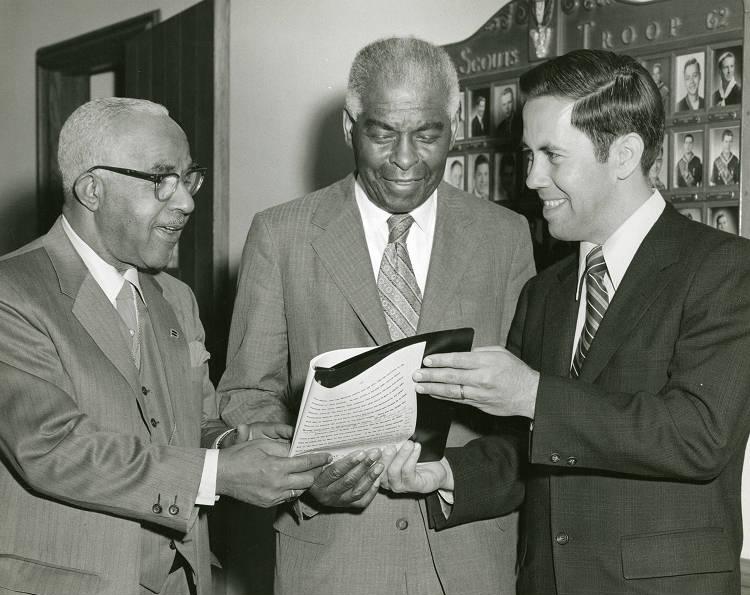 Three men stand together.