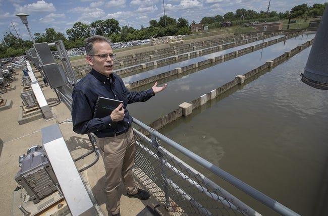 A man stands on a platform in front of a water containment system.