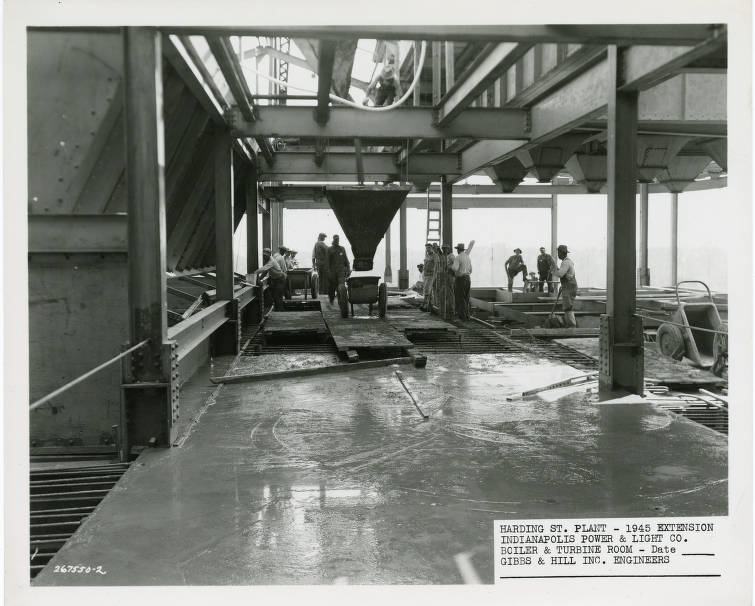 Several men work inside a boiler and turbine room. 