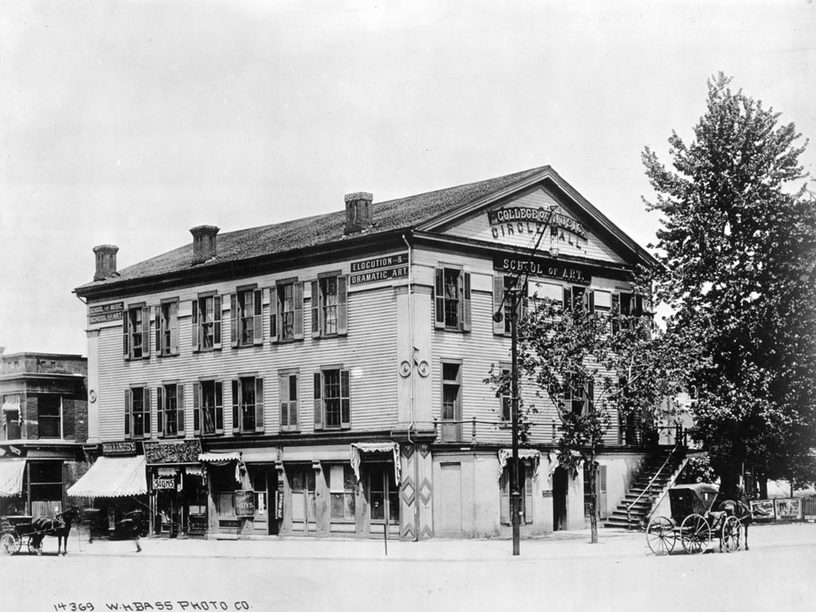 The three-story, rectangular building has a gable roof. The upper two stories have clapboard siding and shutters on the windows. The street level houses various businesses.