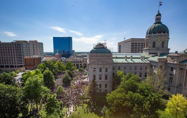 Aerial view of a large crowd of people filling the streets in front of a government building.