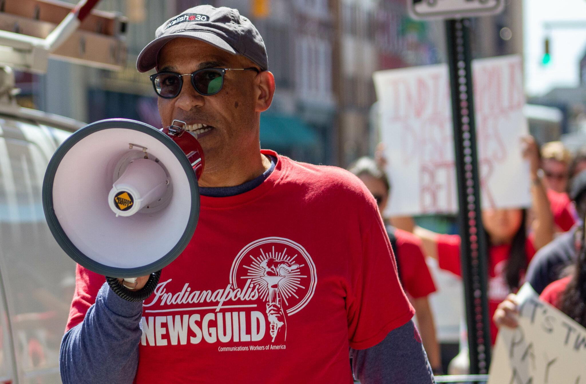 A man stands with a bull horn to his mouth.