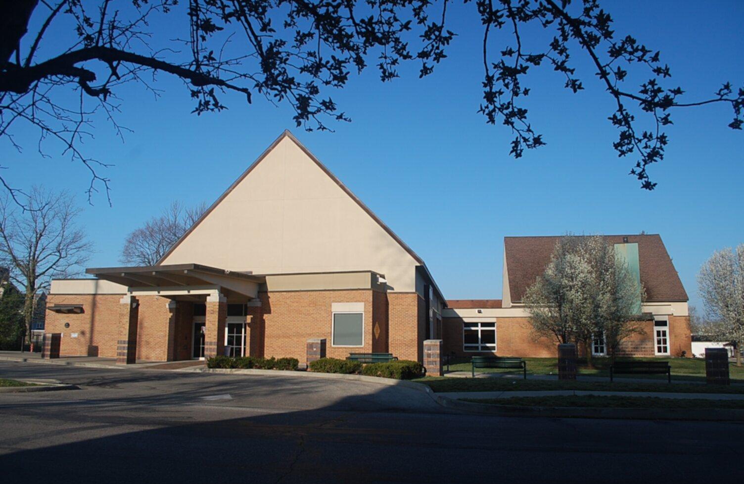 Exterior view of a single story library building with a pointed roof.